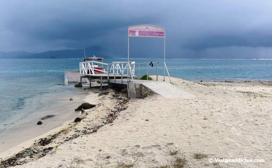 L'embarcador del motu Ofetaro i, al fons, l'illa de Taha'a sota la pluja (Ofetaro, Ra'iātea, illes de la Societat)