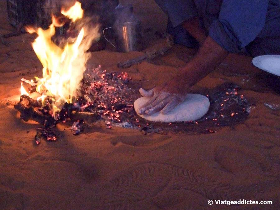 Amasando la «taguella» (el pan tuareg) sobre les brasas antes de cocerla bajo la arena