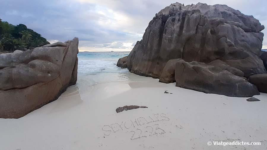 Texto sobre la arena de la playa de Anse Patates (La Digue)