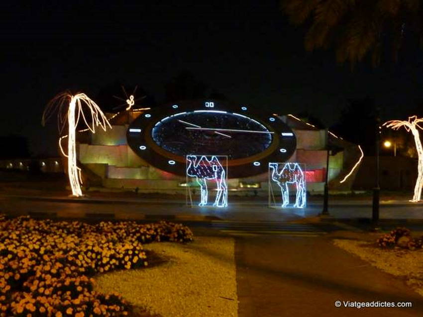 Al Ain (Abu Dhabi, UAE). Huge clock, with electric palm trees and camels ... ultra-modernity in a park at Al Ain